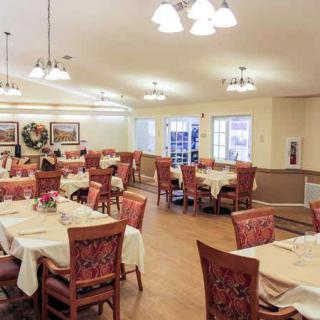 A well-lit dining area with neatly arranged tables and chairs, featuring elegant decor.