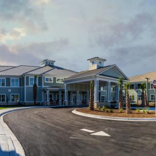 A modern building with a covered entrance and surrounding palm trees.