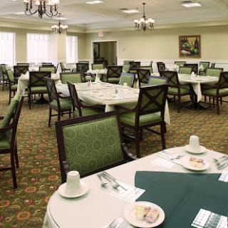 A spacious dining room set up with tables and chairs, featuring green decor and a formal atmosphere.