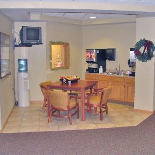 A cozy office break room featuring a dining table and kitchenette.