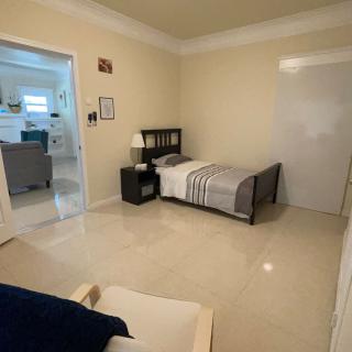 A minimalist bedroom with a single bed, shelf, and lamp on a tile floor.