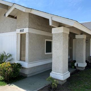 A residential house with a porch and prominent columns under a clear blue sky.