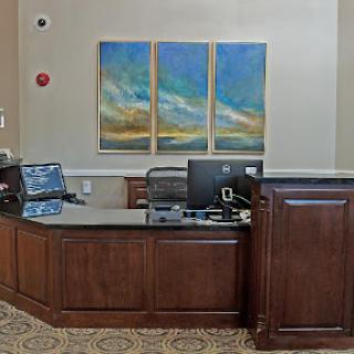 A modern reception area featuring a wooden desk, computers, and abstract artwork on the wall.