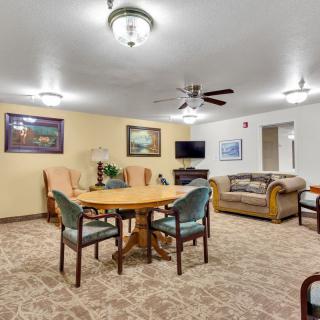 A spacious living room featuring a round table with chairs, a comfortable sofa, and elegant light fixtures.