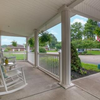 A cozy porch with rocking chairs and hanging plants overlooking a suburban street.