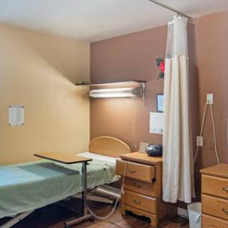 A simple hospital patient room featuring a bed and other essential furniture.