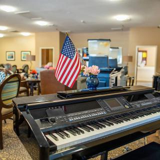A cozy living area with a piano and an American flag, suggesting a community or care facility setting.