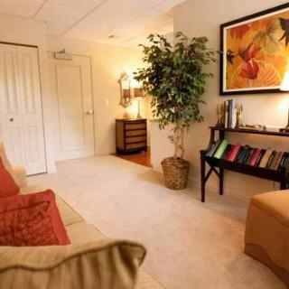 A cozy living room with modern decor, featuring a bookshelf and vibrant artwork.