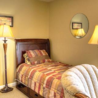 A cozy bedroom with a single bed, armchair, and warm lighting.