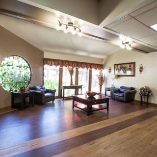 A spacious living room with wooden flooring and ample natural light streaming through large windows.