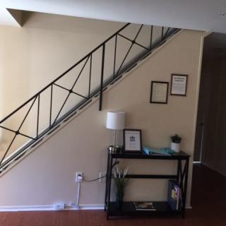 A minimalist interior featuring a staircase with metal railing, wall art, and a console table adorned with decorations.
