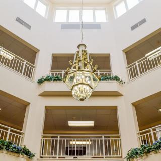 A grand chandelier hanging in a multi-story atrium with balconies and a skylight.