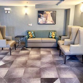 A modern lobby area featuring armchairs, a sofa, and a painting on the wall.