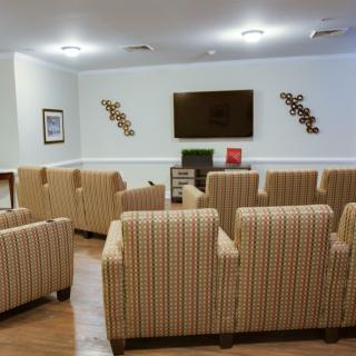 A cozy seating area with multiple chairs arranged in front of a wall-mounted television.