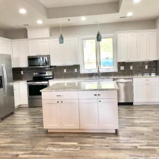 A modern kitchen with white cabinets, a central island, and stainless steel appliances.