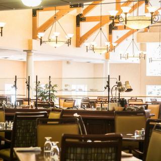 A spacious restaurant dining area with elegant lighting and neatly arranged tables.