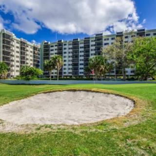 A view of an apartment building overlooking a golf course with a sand trap in the foreground.