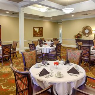 An elegantly set dining room with neatly arranged tables and chairs, featuring classic decor.
