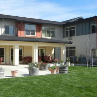 A modern two-story house with a spacious backyard and patio area.