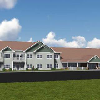 A modern residential building with a spacious lawn under a clear blue sky.