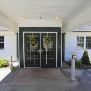 A building entrance with double green doors adorned with wreaths.