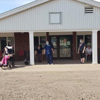 A group of people standing and sitting outside a building entrance during the day.