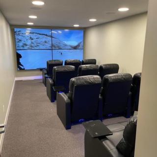 A cozy home theater setup with rows of comfortable cinema chairs facing a large screen.