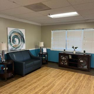 A cozy living room setup featuring a sofa, decorative artwork, and ample natural light.