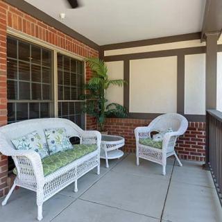 A cozy porch with wicker furniture and a potted plant.