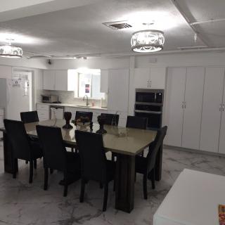 A modern dining area with a large table, multiple chairs, and a view of the kitchen.