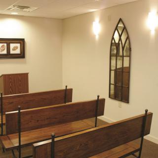 A small chapel interior with wooden benches and a simple, minimalist design.