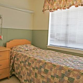 A small bedroom with a single bed, dresser, and window with curtains.