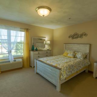 A cozy bedroom with a wooden bed, dresser, and bright yellow accents.