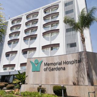 Exterior view of Memorial Hospital of Gardena with palm trees and signage.