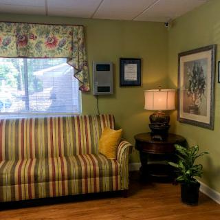 A cozy living room setup featuring a striped sofa, decorative lamp, and indoor plant.