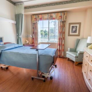 A well-lit and welcoming hospital patient room with a bed and seating area.