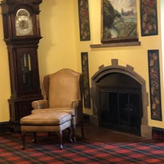 A cozy corner featuring a grandfather clock, an armchair, and a decorative fireplace in a traditionally styled room.