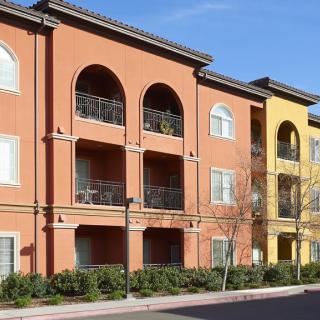 A residential apartment building with multiple balconies on a sunny day.