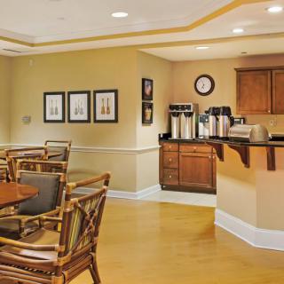 A cozy dining area with a coffee station, featuring wooden tables and chairs.