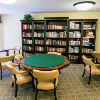 A cozy library room with a round table and bookshelves filled with books.