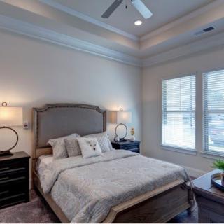 A cozy and elegantly designed bedroom with neutral tones, featuring a stylish bed and bedside lamps.