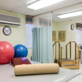 A physical therapy room equipped with exercise balls, a staircase, and other rehabilitation tools.