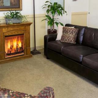 A cozy living room with a leather sofa and a warm fireplace.