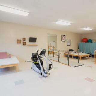A well-equipped therapy room designed for rehabilitation and physical therapy exercises, featuring various exercise equipment and therapy tables.