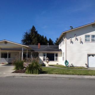 A suburban two-story house with a driveway and garage, surrounded by trees and a well-kept lawn.