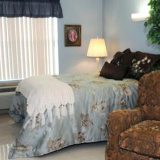 A cozy bedroom with a bed, armchair, and lamp.