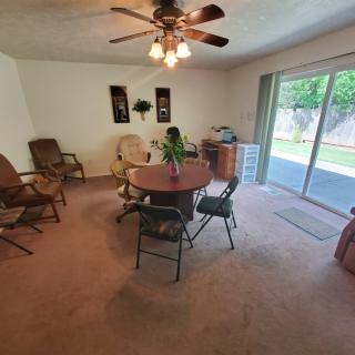A cozy dining room with a round table, surrounded by chairs and featuring a ceiling fan overhead.