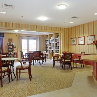 A cozy library interior with tables and chairs surrounded by bookshelves.