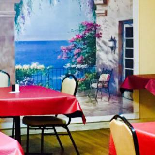 A cozy restaurant dining area featuring a vibrant wall mural and tables with red tablecloths.