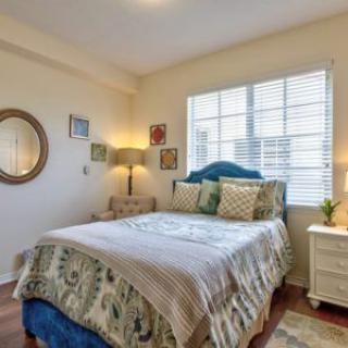 A cozy bedroom with a neatly made bed, decorative pillows, and ambient lighting.